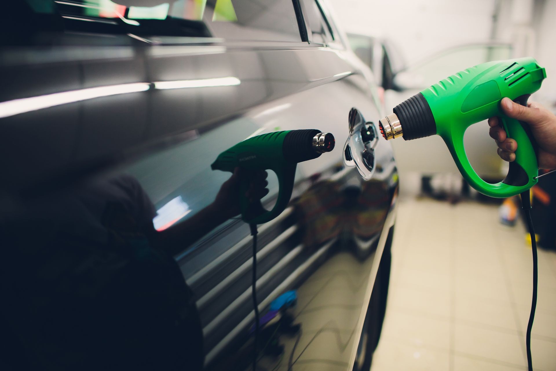 Master installs tint film for car with hairdryer. Concept protection car Master installs tint film for car with hairdryer. Concept protection car